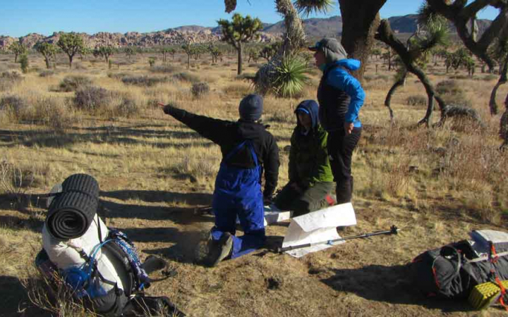 a group of veterans use maps to navigate on an outward bound backpacking course